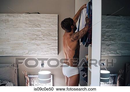 Mid adult man with tattoos selecting shirt from wardrobe View Large Photo Image Stock Image - Mid adult man with tattoos selecting shirt from wardrobe. Fotosearch