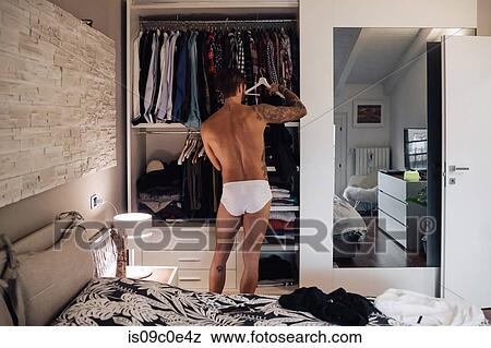 Mid adult man with tattoos selecting clothes from wardrobe, rear view View Large Photo Image Stock Photo - Mid adult man with tattoos selecting clothes from wardrobe, rear view. Fotosearch