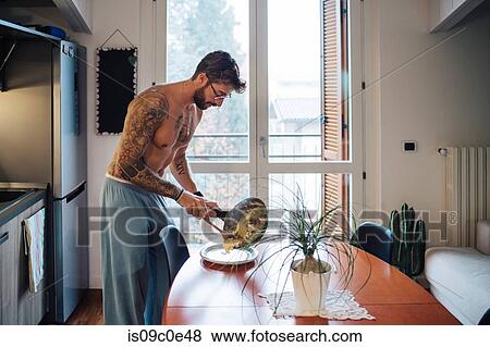 Mid adult man with tattoos serving omelette from frying pan View Large Photo Image Stock Photo - Mid adult man with tattoos serving omelette from frying pan. Fotosearch