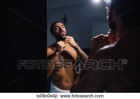 Mid adult man with tattoos trimming beard at bathroom mirror View Large Photo Image Stock Photography - Mid adult man with tattoos trimming beard at bathroom mirror. Fotosearch