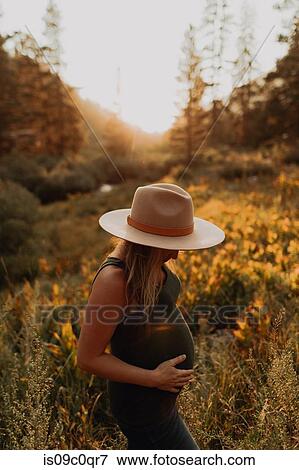 Mid adult pregnant woman in stetson with hands on stomach in rural valley at sunset, Mineral King, California, USA View Large Photo Image Stock Photo - Mid adult pregnant woman in stetson with hands on stomach in rural valley at sunset, Mineral King, California, USA. Fotosearch