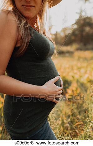 Mid adult pregnant woman in stetson with hands on stomach in rural valley at sunset, cropped, Mineral King, California, USA View Large Photo Image Stock Photo - Mid adult pregnant woman in stetson with hands on stomach in rural valley at sunset, cropped, Mineral King, California, USA. Fotosearch
