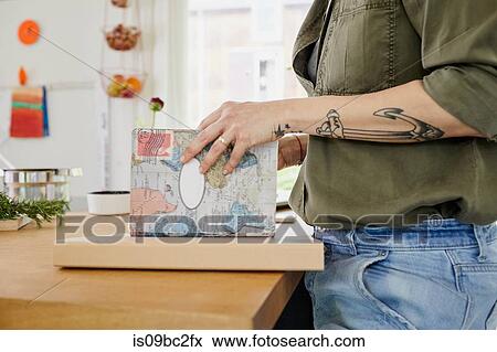 MId adult with tattoos on arm, looking at book in kitchen, mid section View Large Photo Image Stock Photo - MId adult with tattoos on arm, looking at book in kitchen, mid section. Fotosearch