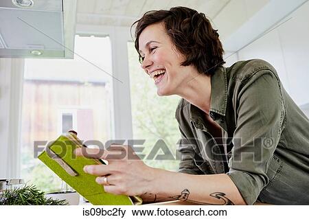 MId adult with tattoos on arm, using digital tablet in kitchen, mid section, laughing View Large Photo Image Stock Photo - MId adult with tattoos on arm, using digital tablet in kitchen, mid section, laughing. Fotosearch