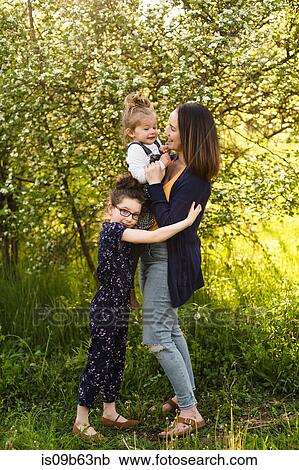 Mid adult woman and daughters in field with blossoming trees View Large Photo Image Stock Image - Mid adult woman and daughters in field with blossoming trees. Fotosearch