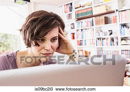 Mid adult woman at home, using laptop, worried expression View Large Photo Image Stock Image - Mid adult woman at home, using laptop, worried expression. Fotosearch