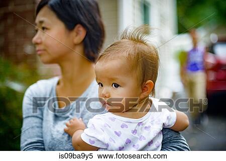 Mid adult woman carrying baby daughter in arms View Large Photo Image Stock Photography - Mid adult woman carrying baby daughter in arms. Fotosearch