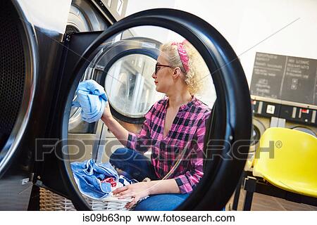 Mid adult woman inserting laundry into washing machine at laundrette View Large Photo Image Stock Photography - Mid adult woman inserting laundry into washing machine at laundrette. Fotosearch