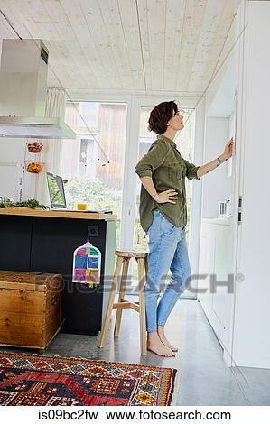 Mid adult woman looking at planner on kitchen wall View Large Photo Image Stock Photo - Mid adult woman looking at planner on kitchen wall. Fotosearch