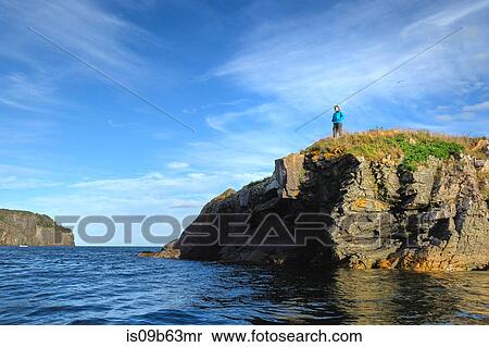 Stock Photography - Mid adult woman looking out from coastal cliff, St John's, Newfoundland, Canada. Fotosearch