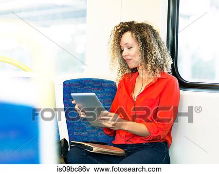 Mid adult woman on train, using digital tablet View Large Photo Image Stock Photo - Mid adult woman on train, using digital tablet. Fotosearch