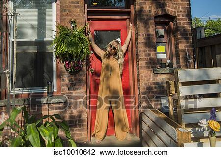 Mid adult woman posing in doorway with arms raised at community garden party, portrait View Large Photo Image Stock Image - Mid adult woman posing in doorway with arms raised at community garden party, portrait. Fotosearch