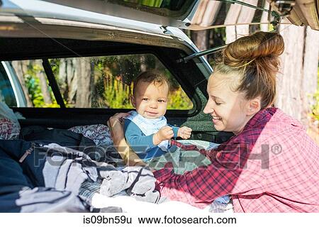 Mid adult woman with baby son sitting up in car boot View Large Photo Image Stock Photograph - Mid adult woman with baby son sitting up in car boot. Fotosearch