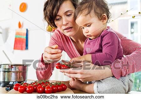 Mother and baby daughter in kitchen, sorting through tomatoes on kitchen counter View Large Photo Image Stock Photograph - Mother and baby daughter in kitchen, sorting through tomatoes on kitchen counter. Fotosearch
