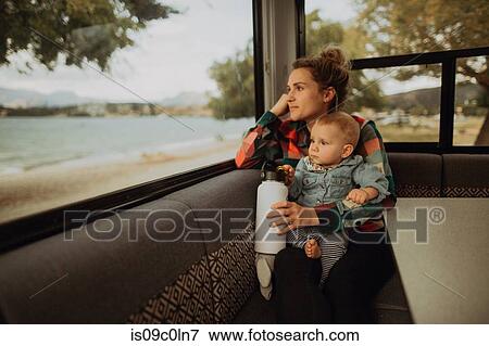 Stock Photo - Mother and baby looking out window of motorhome, Wanaka, Taranaki, New Zealand. Fotosearch