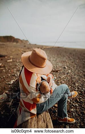 Picture - Mother and baby resting on fallen tree trunk on beach. Fotosearch