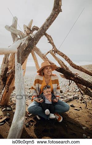 Mother and baby sitting inside wickiup on beach View Large Photo Image Stock Photography - Mother and baby sitting inside wickiup on beach. Fotosearch
