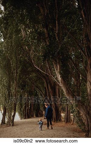 Stock Image - Mother and baby walking on beach, Wanaka, Taranaki, New Zealand. Fotosearch