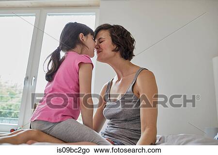 Mother and daughter at home, sitting together, touching noses View Large Photo Image Picture - Mother and daughter at home, sitting together, touching noses. Fotosearch