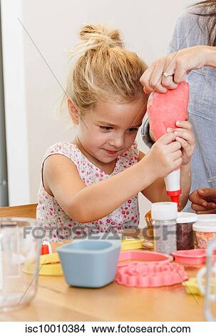 Picture - Mother and daughter decorating cupcake with frosting in kitchen. Fotosearch