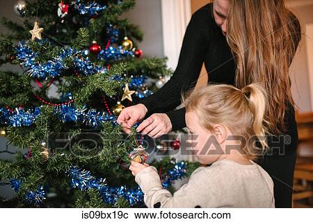 Mother and daughter decorating Christmas tree View Large Photo Image Stock Image - Mother and daughter decorating Christmas tree. Fotosearch