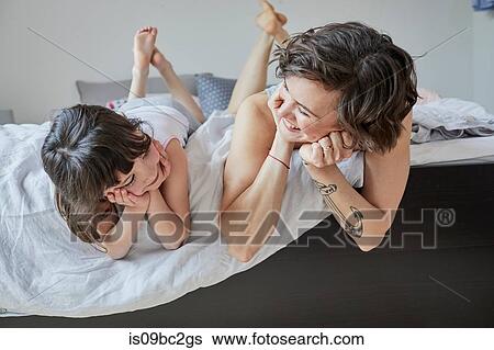 Mother and daughter lying on bed, smiling View Large Photo Image Stock Photograph - Mother and daughter lying on bed, smiling. Fotosearch