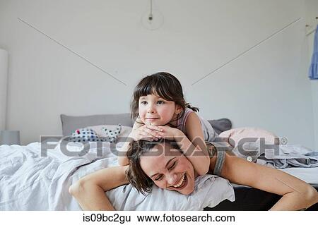 Mother and daughter lying on bed, daughter lying on mother's back View Large Photo Image Stock Photograph - Mother and daughter lying on bed, daughter lying on mother's back. Fotosearch