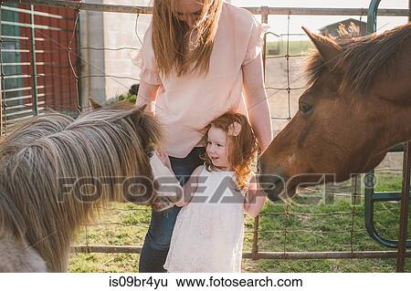 Mother and daughter petting pony in farm View Large Photo Image Stock Photograph - Mother and daughter petting pony in farm. Fotosearch