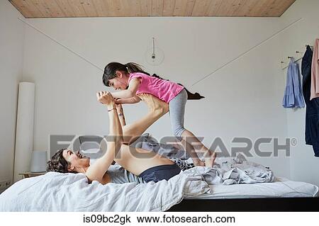 Mother and daughter playing in bedroom, mother balancing daughter on feet View Large Photo Image Stock Image - Mother and daughter playing in bedroom, mother balancing daughter on feet. Fotosearch