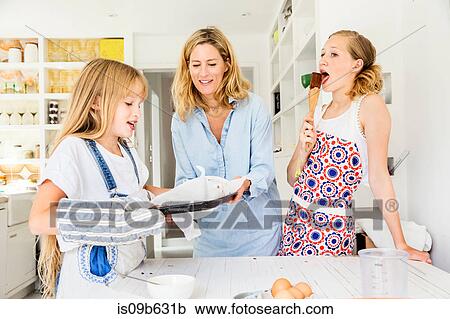 Stock Image - Mother and daughters baking in kitchen. Fotosearch