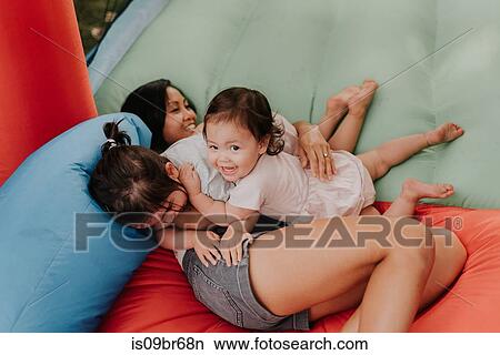 Mother and daughters playing on bouncy castle View Large Photo Image Picture - Mother and daughters playing on bouncy castle. Fotosearch