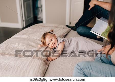 Mother and father on bed with baby daughter with story book, portrait View Large Photo Image Stock Image - Mother and father on bed with baby daughter with story book, portrait. Fotosearch
