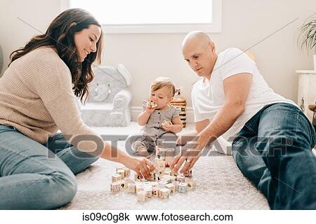 Mother and father on nursery floor with baby daughter playing with building blocks View Large Photo Image Stock Image - Mother and father on nursery floor with baby daughter playing with building blocks. Fotosearch