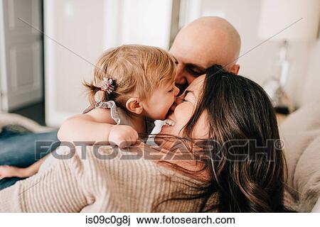 Mother and father reclining on bed together with baby daughter, over the shoulder view View Large Photo Image Stock Image - Mother and father reclining on bed together with baby daughter, over the shoulder view. Fotosearch