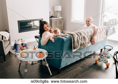 Mother and father reclining on sofa with baby daughter View Large Photo Image Stock Image - Mother and father reclining on sofa with baby daughter. Fotosearch