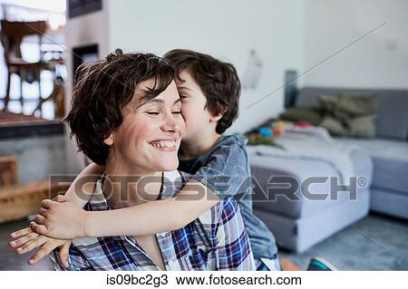 Stock Image - Mother and son at home, son hugging mother. Fotosearch