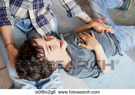 Stock Photograph - Mother and son at home, son lying on mother's legs. Fotosearch