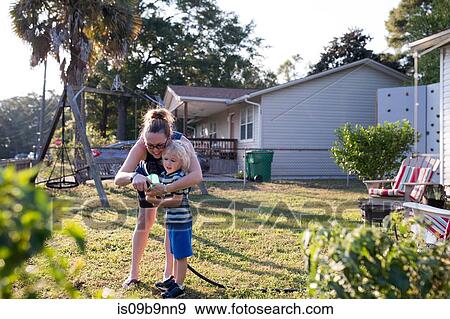 Stock Photo - Mother and son in garden with hosepipe. Fotosearch