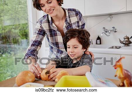 Stock Photo - Mother and son preparing food in kitchen. Fotosearch