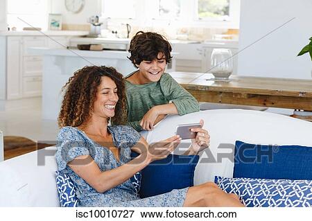 Stock Photo - Mother and son smiling at text message on cellphone. Fotosearch