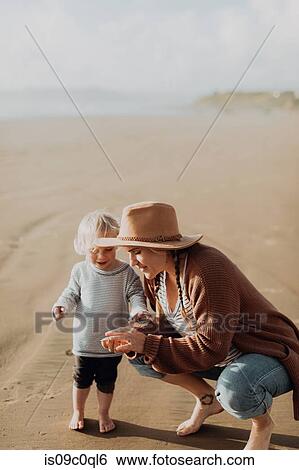 Stock Photograph - Mother and toddler playing on beach. Fotosearch
