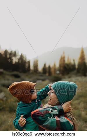 Stock Photograph - Mother carrying toddler daughter, wearing knit hats in rural valley, Mineral King, California, USA. Fotosearch