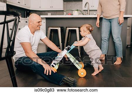 Mother father playing with baby daughter in kitchen View Large Photo Image Stock Image - Mother father playing with baby daughter in kitchen. Fotosearch
