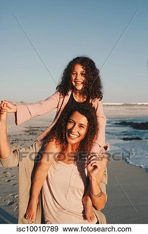 Mother giving daughter piggyback ride on beach View Large Photo Image Stock Photo - Mother giving daughter piggyback ride on beach. Fotosearch