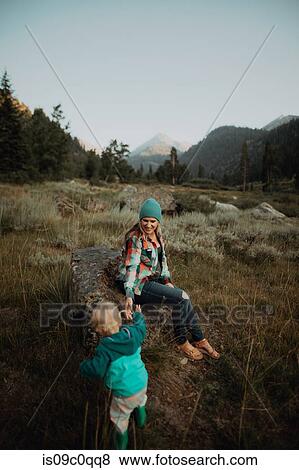 Stock Photo - Mother giving toddler daughter helping hand to sit on boulder in rural valley, Mineral King, California, USA. Fotosearch
