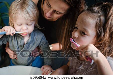 Stock Photo - Mother helping children brush teeth. Fotosearch