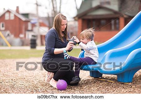 Mother helping son with shoe on slide View Large Photo Image Stock Photo - Mother helping son with shoe on slide. Fotosearch