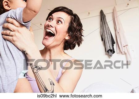 Mother holding baby daughter, face to face, excited expression View Large Photo Image Stock Image - Mother holding baby daughter, face to face, excited expression. Fotosearch