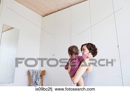 Mother holding baby girl, looking in mirror, low angle view View Large Photo Image Stock Image - Mother holding baby girl, looking in mirror, low angle view. Fotosearch