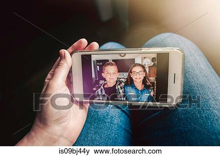 Mother holding smartphone with picture message of twin girl and boy, personal perspective View Large Photo Image Stock Photo - Mother holding smartphone with picture message of twin girl and boy, personal perspective. Fotosearch